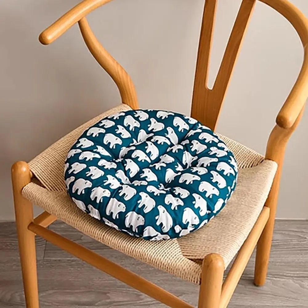 Round chair cushion with polar bear motifs on deep blue – shown in a room setting