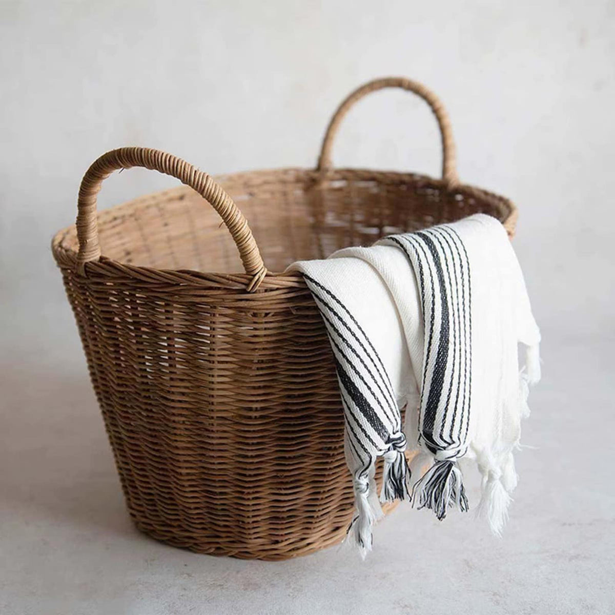 Woven rattan basket holding a striped linen throw