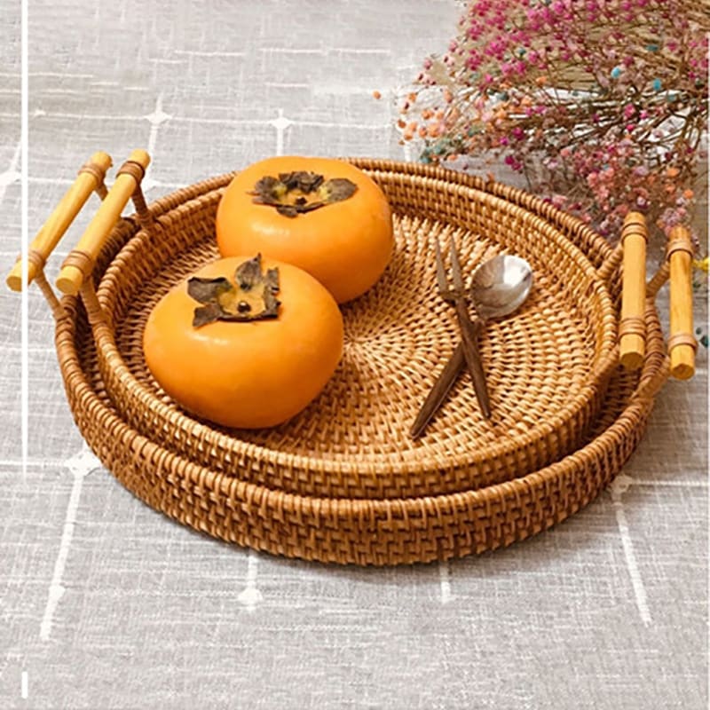 Handwoven rattan serving tray with light wood handles – shown in a room setting